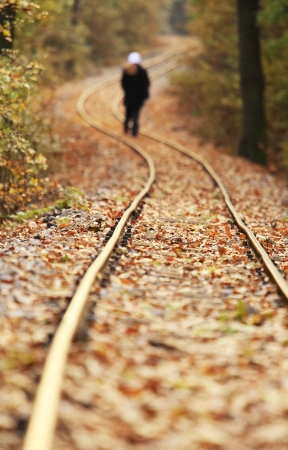 Train track covered with fallen leaves in autumn with walking personの写真素材