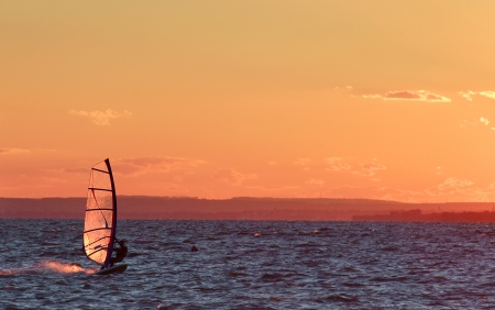 Windsurfer go fast on lake beautiful colors at sundown の写真素材