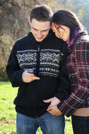Portrait of romantic young couple in autumn outdoor with mobile phoneの写真素材