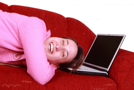 Young women is resting on the couch and surfing the internet on her laptop computerの写真素材