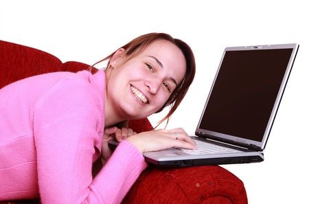 Young women is resting on the couch and surfing the internet on her laptop computerの写真素材
