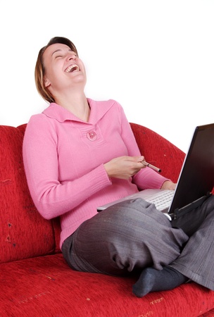 Young woman laugh with laptop on red couchの写真素材