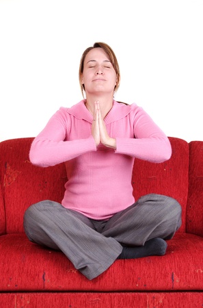 Young woman in yoga position on red couch at homeの写真素材