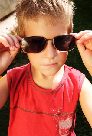Young child wearing glasses with serious look outdoorの写真素材