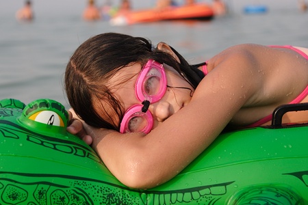 Young girl with diving goggles relax on floater crocodile at the beachの写真素材