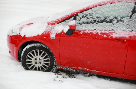 Snow covered red car in winterの写真素材