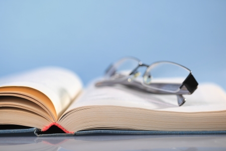 Open book on blue with eyeglassesの写真素材