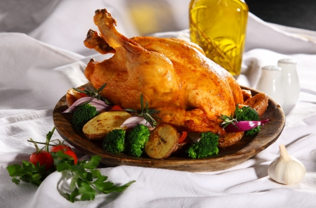 Roasted whole chicken on a plate with vegetablesの写真素材