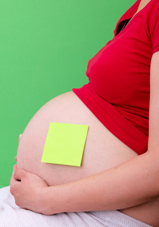 Pregnant woman with stick notes on her bellyの写真素材