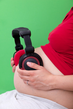 Pregnant woman with headphones on her stomachの写真素材