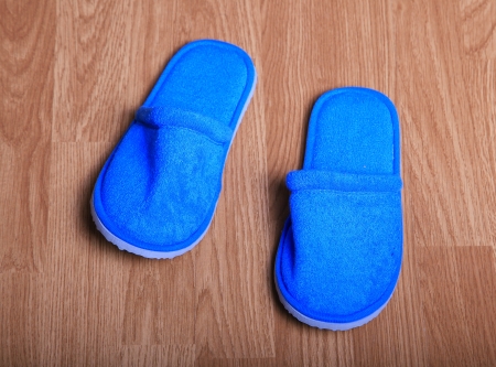 Blue house slippers on the brown wood floorの写真素材