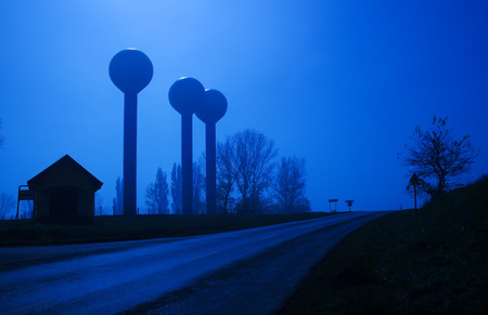Community public water tower utility and road at nightの写真素材