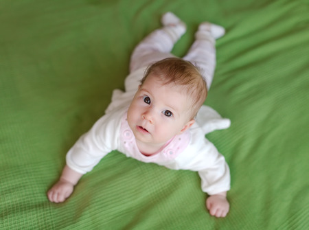 Cute young child lying on green blanket and looking upの写真素材