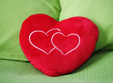 Heart shape pillow on green backgroundの写真素材