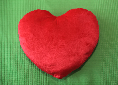 Heart shape pillow on green backgroundの写真素材