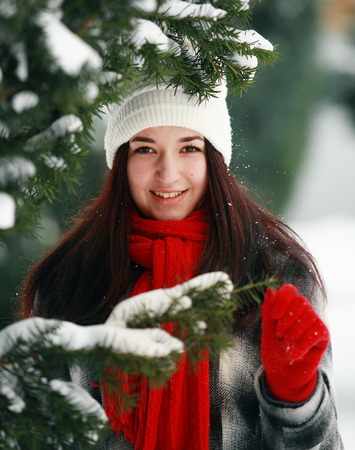 Young beautiful woman behind snow covered pine in winterの写真素材