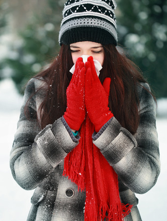 Young beautiful woman outdoor blowing nose in winterの写真素材