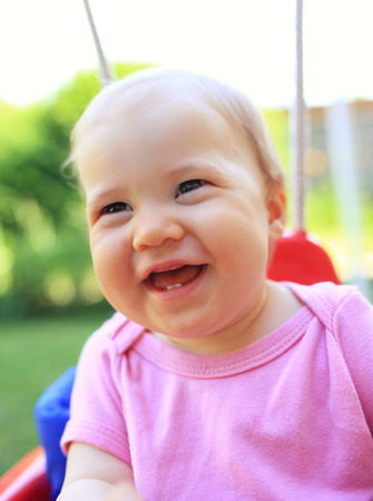 Young cute child smiling in swingの写真素材