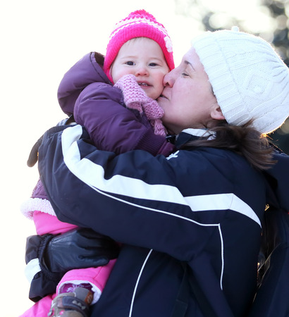 Young woman with her lovely child outdoor in winterの写真素材