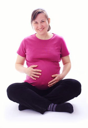 Young happy pregnant woman sitting on floor, isolated imageの写真素材