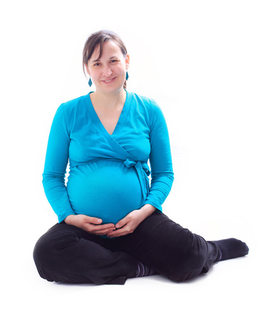 Young happy pregnant woman sitting on floor, isolated imageの写真素材