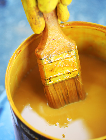 Bucket with yellow paint with paintbrushの写真素材