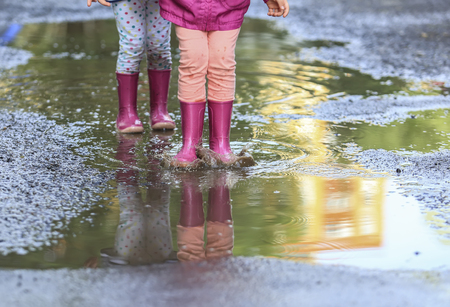 Playful child outdoor jump in puddle in boot after rainの写真素材