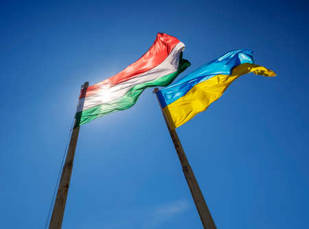 Flags of Hungary Ukraine and European Union waving on pole against blue skyの写真素材