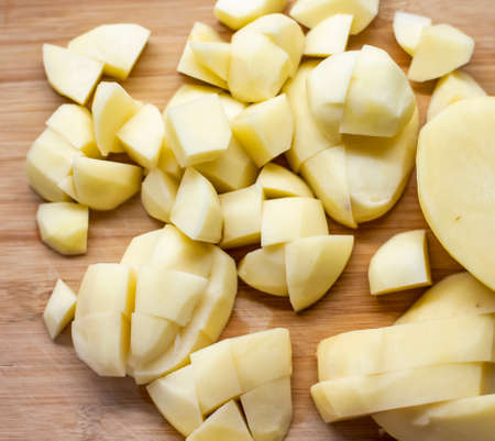 Chopped uncooked raw potato on a wooden plateの写真素材