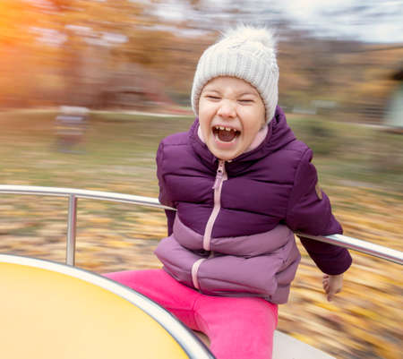 Young happy child merry go round outdoor in autumnの写真素材