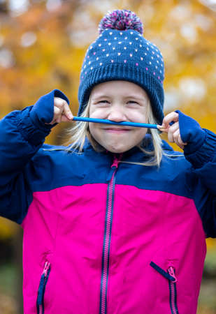 Portrait of joyful funny child with pencil mustache outdoorの写真素材