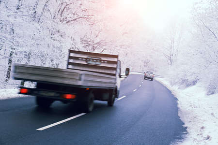 truck driving on the road in the winter forest, motion blurの写真素材