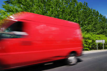 Blurred motion of a red delivery truck on the road in summerの写真素材