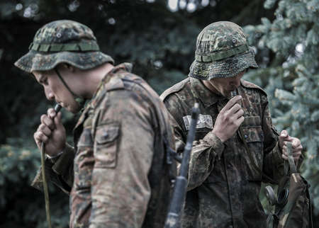 Two young men in military uniforms with a weapon in their hands.の写真素材