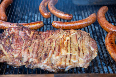 Fatty steak with sausauges is grilled on the gridの写真素材