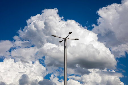 Sky with fluffy clouds with blue background and street lampの写真素材