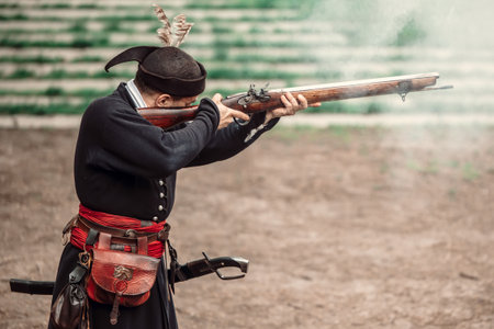 Man firing with old gun wearing traditional clothes from middle agesの写真素材