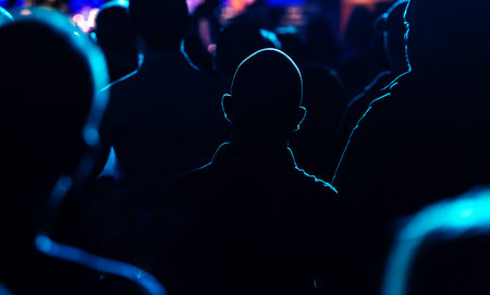 Excited audience watching a live band performance on stage with raised hands and dramatic concert...