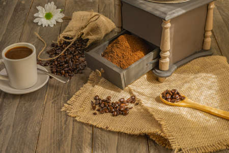 coffee beans and ground coffee with coffee grinder and flowersの写真素材