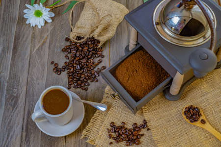 coffee beans and ground coffee with coffee grinder and flowersの写真素材