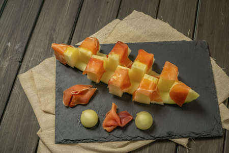juicy melon with ham typical summer food on dark backgroundの写真素材
