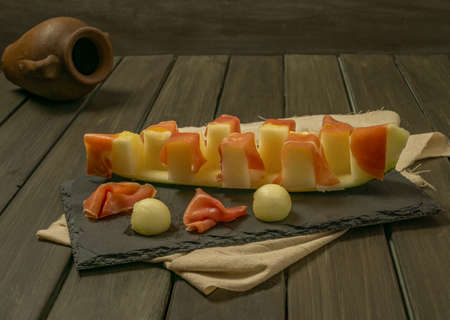 juicy melon with ham typical summer food on dark backgroundの写真素材