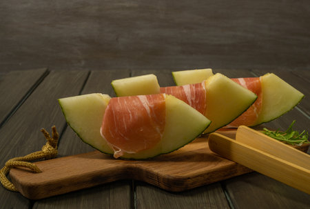juicy melon with ham typical summer food on dark backgroundの写真素材