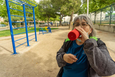 obese senior woman doing sports in the park slimming diet with face maskの写真素材