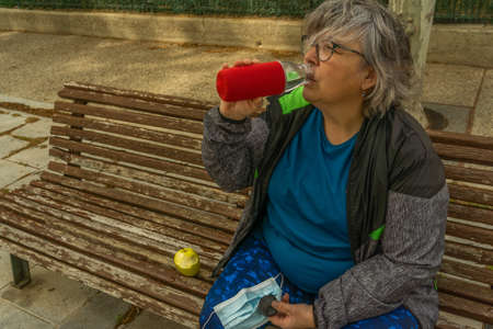 obese senior woman doing sports in the park slimming diet with face maskの写真素材