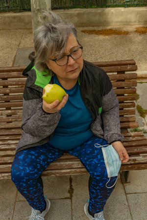 obese senior woman doing sports in the park slimming diet with face maskの写真素材
