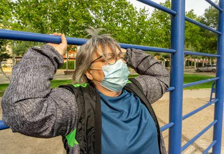 obese senior woman doing sports in the park slimming diet with face maskの写真素材