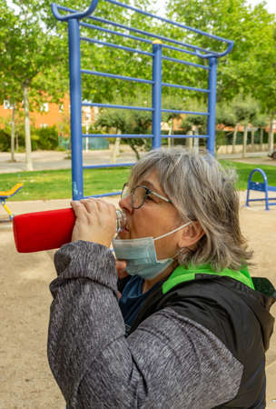 obese senior woman doing sports in the park slimming diet with face maskの写真素材