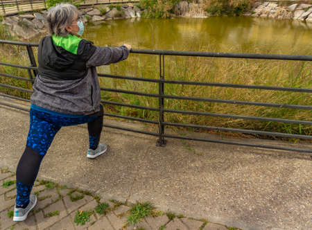 obese senior woman doing sports in the park slimming diet with face maskの写真素材