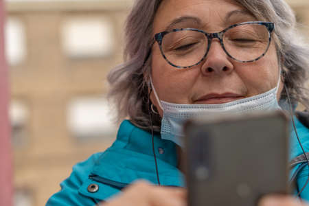 white haired woman drinking coffee at the bar while writing and looking at the phone